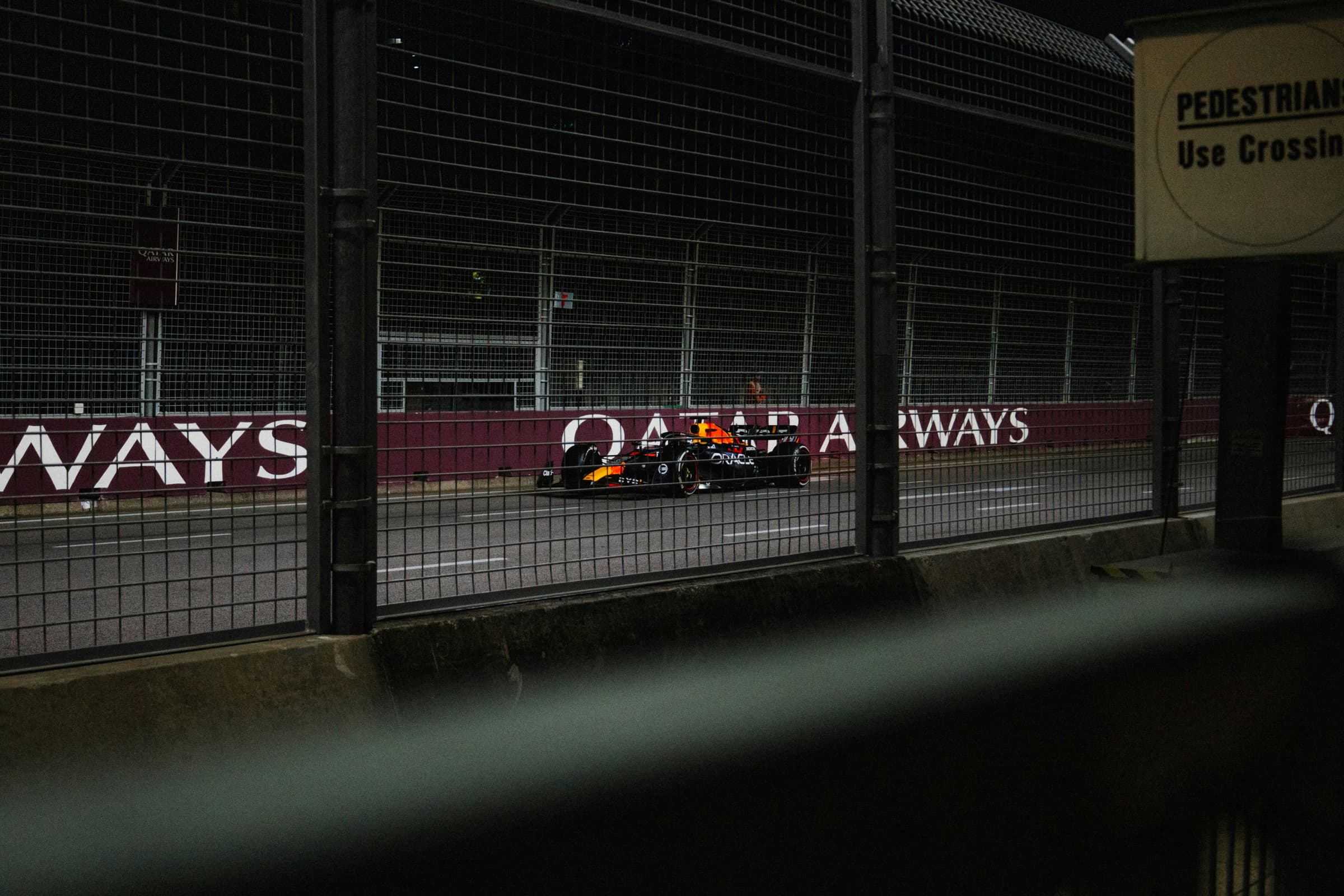 A Formula 1 car at night behind the catch fence of the Marina Bay street circuit