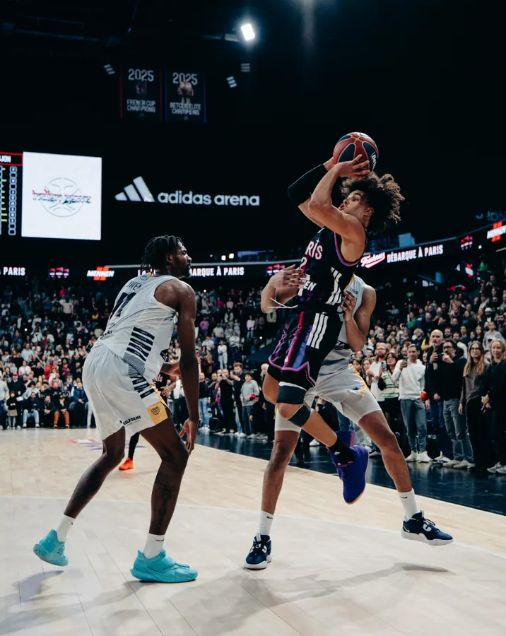 A basketball player rising for a jump shot in a packed arena